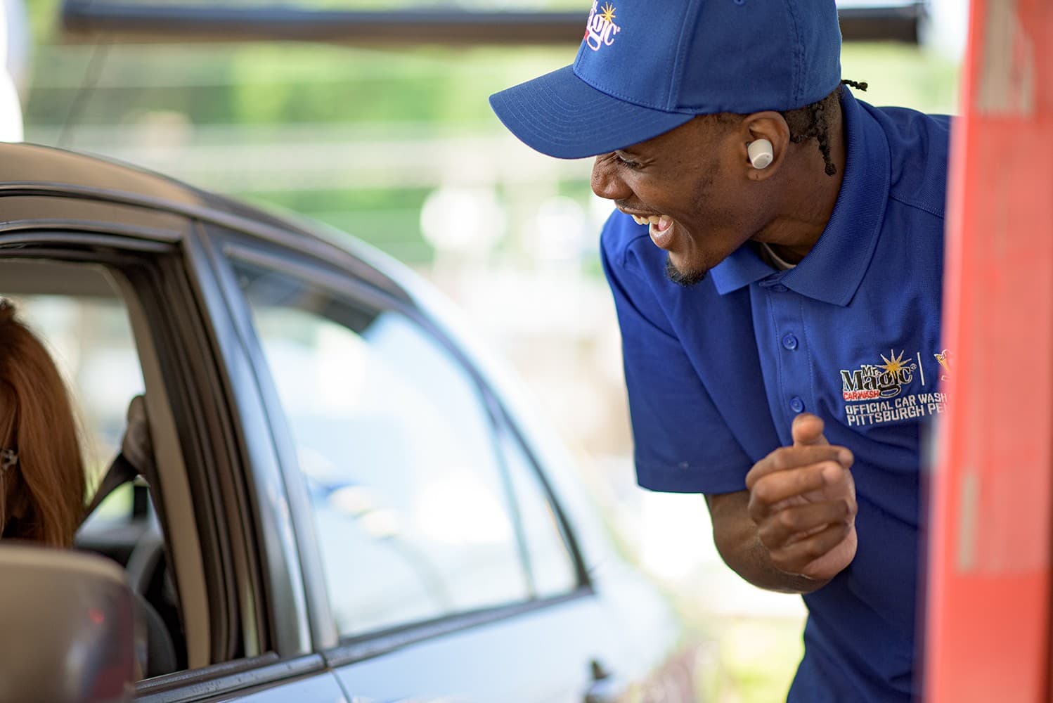 A Mr. Magic team member laughing with a driver at the pay lane