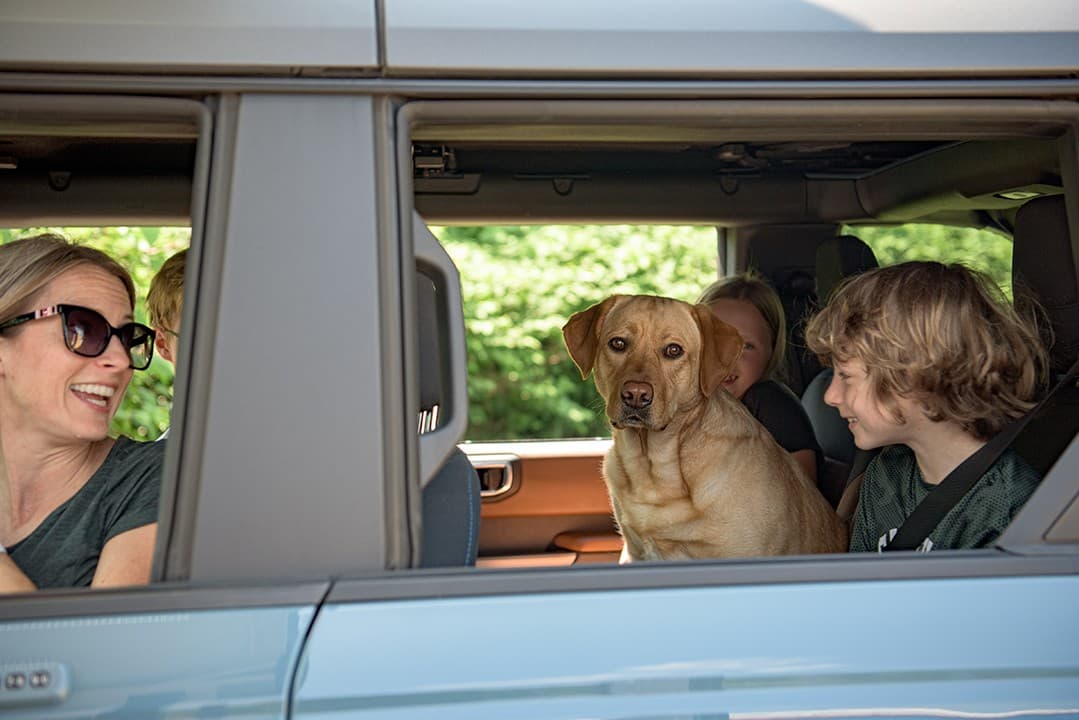 A family and their dog smiling from the car window