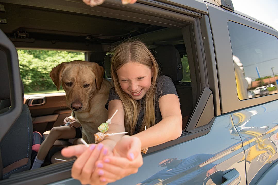A girl and her dog leaning out of the car window